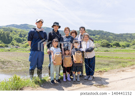 插秧後，一家三代人在稻田裡笑容滿面，手裡拿著收割的稻穀。 140441152
