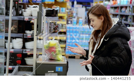 Customer using a digital scale to weigh fresh bell peppers in a plastic bag before buying them at a supermarket Customer using a digital scale to weigh fresh bell peppers in a plastic bag before buying them at a supermarket 140441255