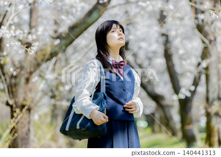 A portrait of a high school girl enjoying spring under a row of cherry trees. 140441313