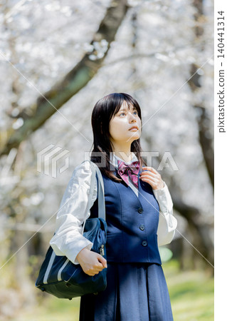 A portrait of a high school girl enjoying spring under a row of cherry trees. A portrait of a high school girl enjoying spring under a row of cherry trees. 140441314