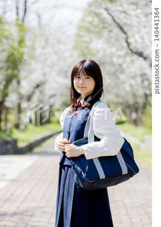A spring portrait of a high school girl walking to school with a row of cherry trees in the background. 140441364