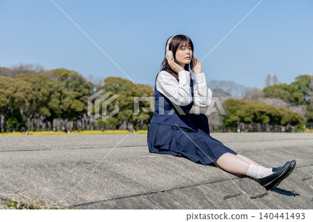 High school girls enjoying music under the blue sky and a sprawling copy space High school girls enjoying music under the blue sky and a sprawling copy space 140441493