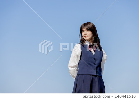A portrait of a high school girl standing against a blue sky. A portrait of a high school girl standing against a blue sky. 140441516