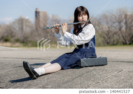 一位高中女生在藍天下吹奏長笛。 一位高中女生在藍天下吹奏長笛。 140441527