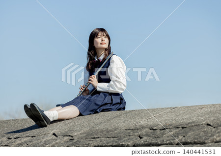 一位高中女生在藍天下吹奏長笛。 一位高中女生在藍天下吹奏長笛。 140441531
