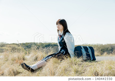 A high school girl smiles while relaxing in a meadow. A high school girl smiles while relaxing in a meadow. 140441550