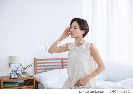 A woman is feeling unwell in the morning and has a headache. 140441852