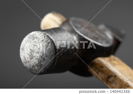Selective focus macro shot of a weathered steel hammer face with a rustic wooden handle Selective focus macro shot of a weathered steel hammer face with a rustic wooden handle 140442388