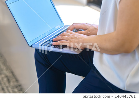 一位女士的手正在膝上的筆記型電腦上打字。 一位女士的手正在膝上的筆記型電腦上打字。 140443761