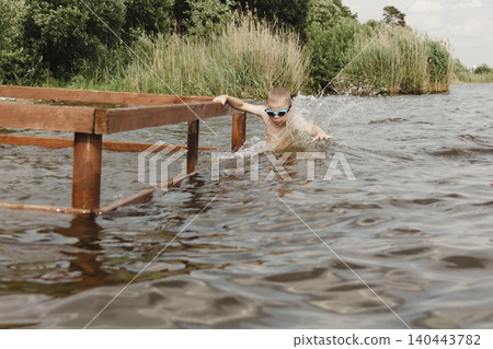 dynamic, relaxed shot boy jumping into natural lake. child is captured mid flight, creating sense excitement. image perfect family vacations, water safety, promoting active lifestyle among children dynamic, relaxed shot boy jumping into natural lake. child is captured mid flight, creating sense excitement. image perfect family vacations, water safety, promoting active lifestyle among children 140443782