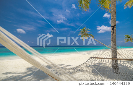 Beautiful tropical beach hammock framed by leaning palms. Crystal turquoise sea beyond swaying fronds. Dreamy paradise island hideaway in soft sunlight. Inspirational summer vacation travel background Beautiful tropical beach hammock framed by leaning palms. Crystal turquoise sea beyond swaying fronds. Dreamy paradise island hideaway in soft sunlight. Inspirational summer vacation travel background 140444359