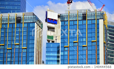 Crane on the construction site in a site surrounded by the high buildings. Office building under construction in the vicinity of high apartment buildings and office building. Crane on the construction site in a site surrounded by the high buildings. Office building under construction in the vicinity of high apartment buildings and office building. 140444568