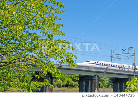 Under a clear sky, the Tokaido Shinkansen N700S runs through the lush greenery of Nineteen-Nine Pond. Under a clear sky, the Tokaido Shinkansen N700S runs through the lush greenery of Nineteen-Nine Pond. 140444726