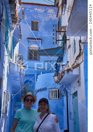 Mature travelers enjoy their vacation posing together on a picturesque blue street in Chefchaouen Mature travelers enjoy their vacation posing together on a picturesque blue street in Chefchaouen 140445114