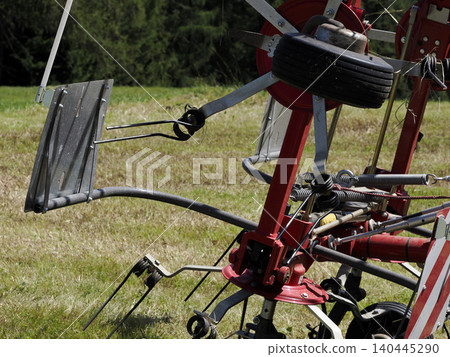 Red Hay Tedder Farm Machinery Closeup On Grass Field Agricultural Equipment For Haymaking Red Hay Tedder Farm Machinery Closeup On Grass Field Agricultural Equipment For Haymaking 140445290