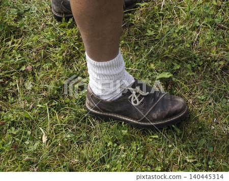 Dolomites Casual outdoor scene of a worn leather shoe and thick white sock on grassy ground, showing a relaxed, rustic mood and everyday footwear details with visible dirt and texture. Dolomites Casual outdoor scene of a worn leather shoe and thick white sock on grassy ground, showing a relaxed, rustic mood and everyday footwear details with visible dirt and texture. 140445314