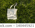 Blank reusable tote bag on green grass in sunlight ,sustainable lifestyle 140445921