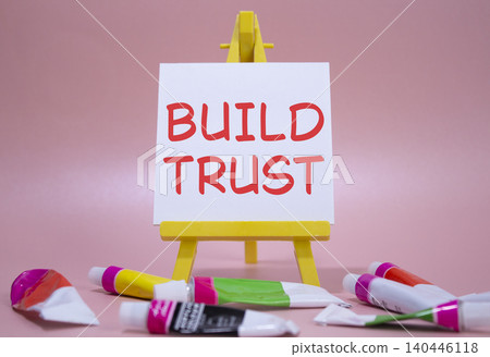 Build trust symbol. Wooden blocks with words Build trust. Beautiful pink background with paints and easel. Business and Build trust concept. Copy space. Build trust symbol. Wooden blocks with words Build trust. Beautiful pink background with paints and easel. Business and Build trust concept. Copy space. 140446118