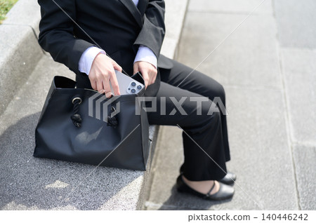 一位二十多歲的日本女職員從包包裡拿出她的智慧型手機。 140446242