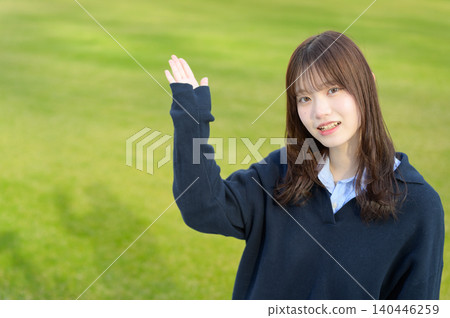 日本女高中生在草坪前舉起了手 日本女高中生在草坪前舉起了手 140446259