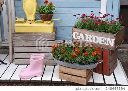 Colorful garden shop display with potted flowers, wooden crates and vintage scale outside storefront 140447164
