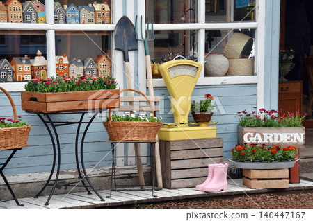 Colorful garden shop display with potted flowers, wooden crates and vintage scale outside storefront Colorful garden shop display with potted flowers, wooden crates and vintage scale outside storefront 140447167