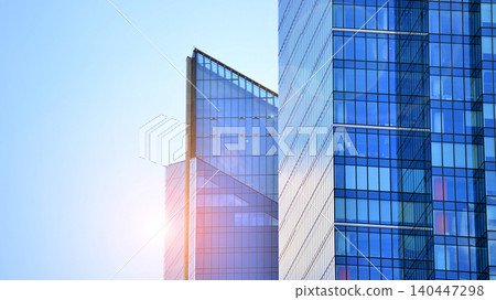 Modern office building with glass facade on a clear sky background. Transparent glass wall of office building. Modern office building with glass facade on a clear sky background. Transparent glass wall of office building. 140447298