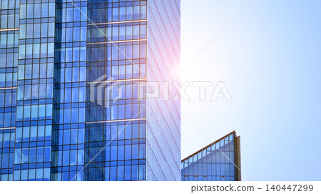 Modern office building with glass facade on a clear sky background. Transparent glass wall of office building. Modern office building with glass facade on a clear sky background. Transparent glass wall of office building. 140447299