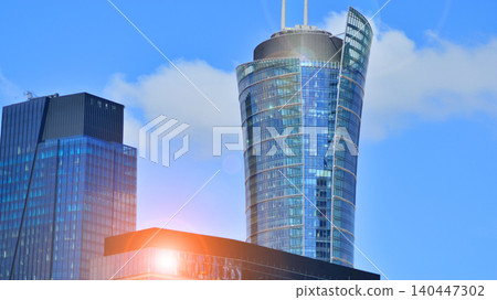 Modern office building with glass facade on a clear sky background. Transparent glass wall of office building. Modern office building with glass facade on a clear sky background. Transparent glass wall of office building. 140447302