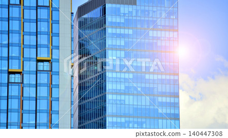 Modern office building with glass facade on a clear sky background. Transparent glass wall of office building. Modern office building with glass facade on a clear sky background. Transparent glass wall of office building. 140447308
