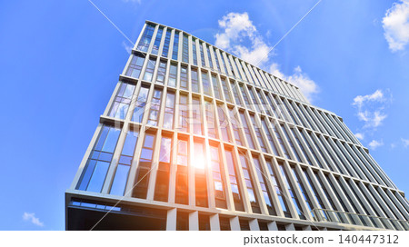 Modern office building with glass facade on a clear sky background. Transparent glass wall of office building. 140447312