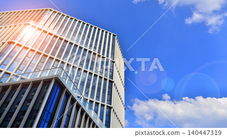 Modern office building with glass facade on a clear sky background. Transparent glass wall of office building. Modern office building with glass facade on a clear sky background. Transparent glass wall of office building. 140447319