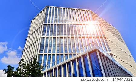 Modern office building with glass facade on a clear sky background. Transparent glass wall of office building. Modern office building with glass facade on a clear sky background. Transparent glass wall of office building. 140447321