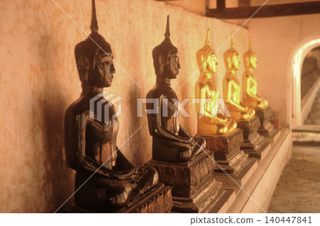 The ancient Buddha images are lined up in the cloister on a Church of Wat Khanon, which also serves as a venue for traditional Thai shadow puppet shows in Thailand. The ancient Buddha images are lined up in the cloister on a Church of Wat Khanon, which also serves as a venue for traditional Thai shadow puppet shows in Thailand. 140447841