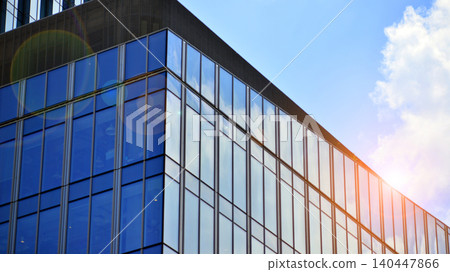 Modern office building with glass facade on a clear sky background. Transparent glass wall of office building. Modern office building with glass facade on a clear sky background. Transparent glass wall of office building. 140447866