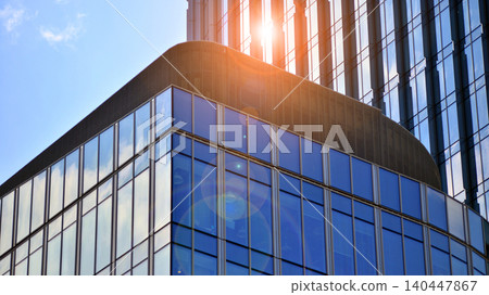 Modern office building with glass facade on a clear sky background. Transparent glass wall of office building. Modern office building with glass facade on a clear sky background. Transparent glass wall of office building. 140447867