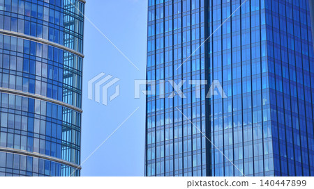 Modern office building with glass facade on a clear sky background. Transparent glass wall of office building. Modern office building with glass facade on a clear sky background. Transparent glass wall of office building. 140447899