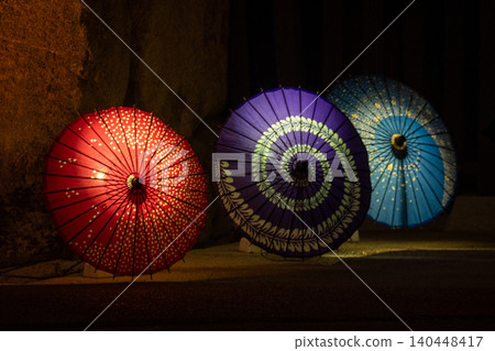 Colorful Japanese umbrellas illuminated in the garden at night Colorful Japanese umbrellas illuminated in the garden at night 140448417