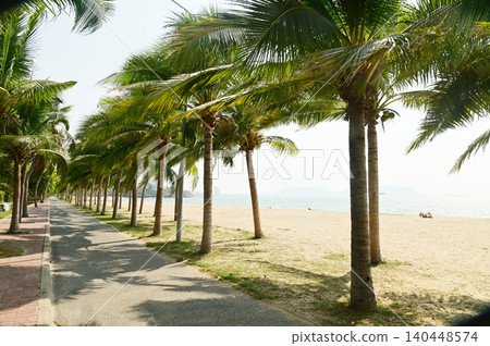 The pavement along the beach in Ban Amphoe is lined with a straight line of coconut trees on both sides. Thailand. The pavement along the beach in Ban Amphoe is lined with a straight line of coconut trees on both sides. Thailand. 140448574