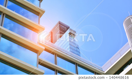 View of modern office building with many windows against clear sky. Glass facade wall. View of modern office building with many windows against clear sky. Glass facade wall. 140448616