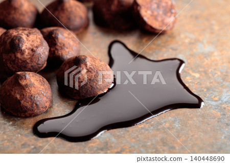 Chocolate truffles and chocolate sauce against a rusty background. 140448690