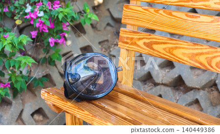 Abandoned snorkeling mask hanging on a bench, a forgotten treasure left behind by its owner, capturing the essence of summer adventures and ocean exploration 140449386