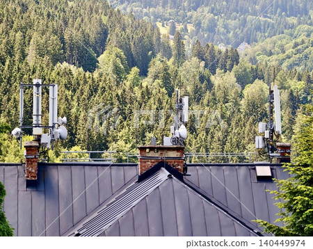 Cellular antennas on rooftop against forested mountain slope Cellular antennas on rooftop against forested mountain slope 140449974