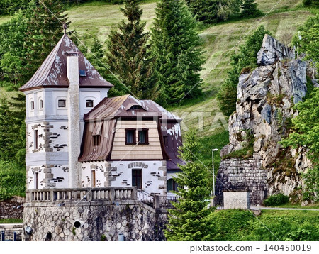 Historic stone villa with tower on grassy hillside 140450019