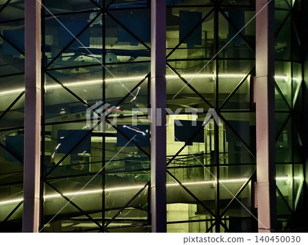 Modern glass facade with illuminated interior ramps and structural steel grid Modern glass facade with illuminated interior ramps and structural steel grid 140450030