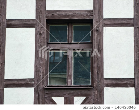 Weathered timber frame wall with old painted plaster and central window Weathered timber frame wall with old painted plaster and central window 140450046