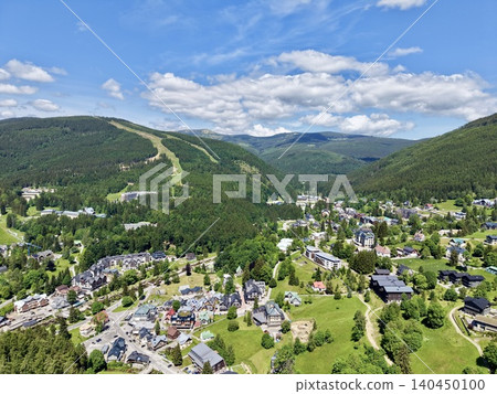 Mountain resort village nestled in green valley under blue sky Mountain resort village nestled in green valley under blue sky 140450100