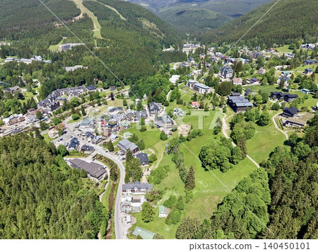 Aerial view of a mountain village surrounded by forested hills 140450101