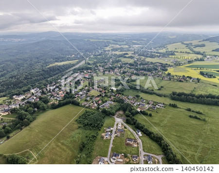 Aerial view of rural village and patchwork farmland under overcast sky 140450142