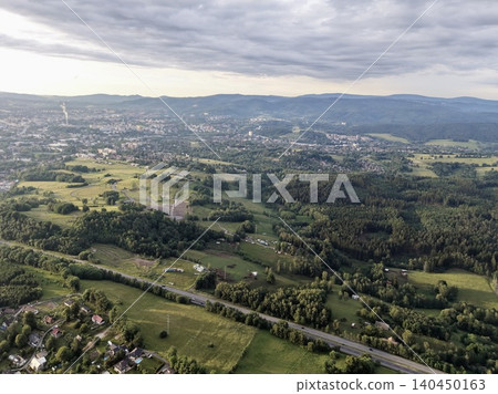 Aerial view of green countryside with rolling hills and distant town Aerial view of green countryside with rolling hills and distant town 140450163